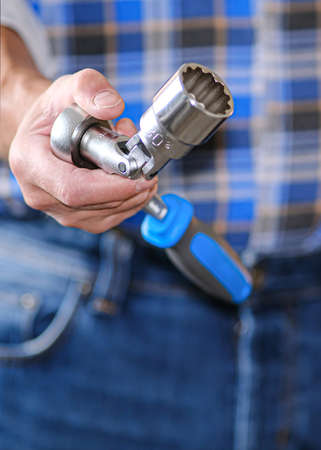 A locksmith in a checked shirt holds a key in his hand. Universal key for any locksmith work.