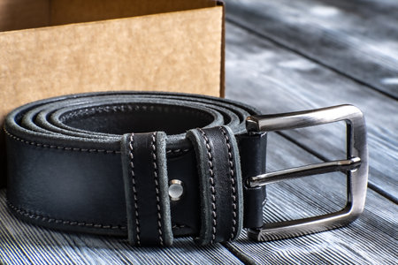 The belt is rolled up, next to a gift box. Template for the design of leather accessories. Background, shiny metal belt buckle. Abstract background. Texture background.の写真素材
