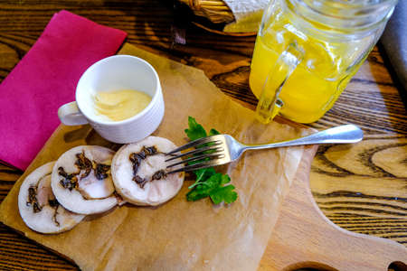 Appetizer in a restaurant, serving on a cutting Board. Rings chicken roulade with dried plums herbs and sauce in the gravy boatの写真素材