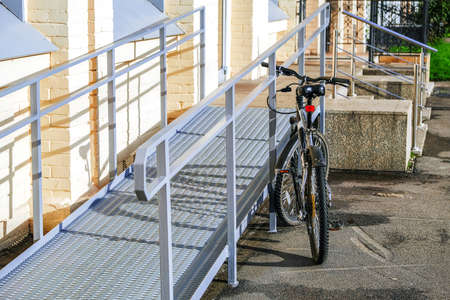 A ramp for wheelchairs. The bike is in the foreground, attached to the railing with an anti-theft cable and lockedの写真素材