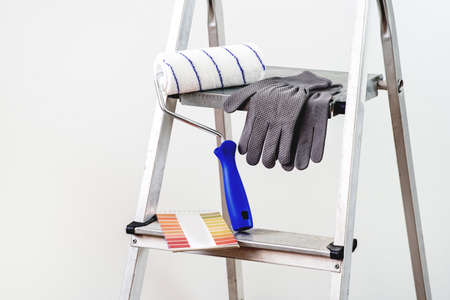 Everything for painting, roller, gloves and sheet for choosing shades. A stepladder in the background.の写真素材