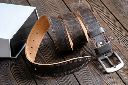 The belt is rolled up, next to a gift box. Template for the design of leather accessories....