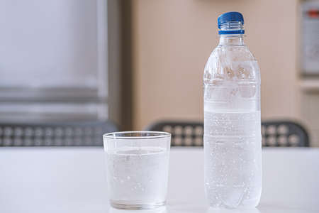 bottle of fresh water backlighting on background with water droplets
