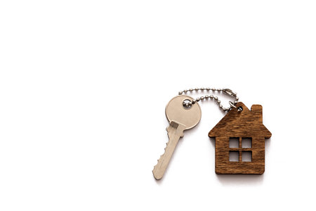 A key with a keychain in the form of a house on a white background. The concept of buying, renting, and insuring housing. Real estate transactions. Copy spaceの写真素材