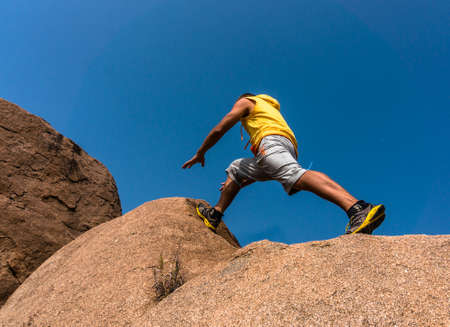 Hiker jumping over the rock