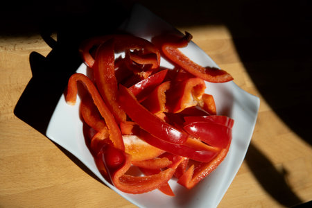 red pepper slices on wood with lights and shadowsの写真素材