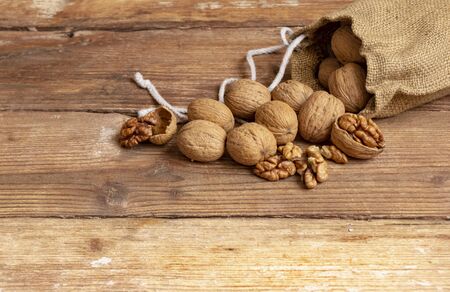Walnut kernels and whole walnuts on old wooden tableの写真素材