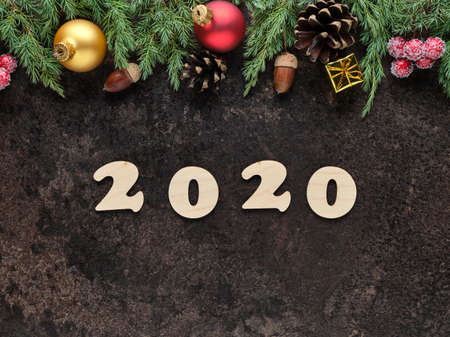 Happy New Year festive background with wooden numbers 2020 and Christmas decorations on a dark stone...