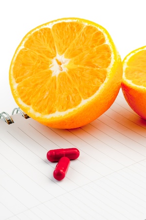 detail an orange and capsule on notepadの写真素材