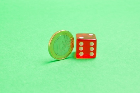 euro coin near the dice on green backgroundの写真素材