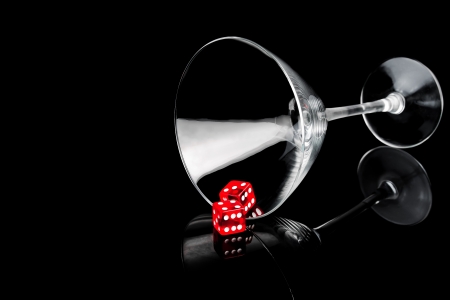 two red dice in a cocktail glass on black background with space for textの写真素材