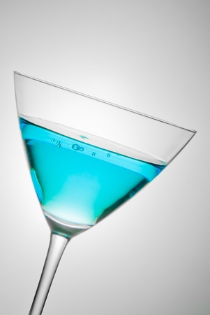 glass with blue cocktail tilted on grey backgroundの写真素材