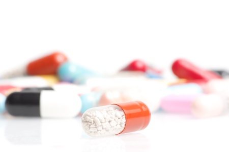 one medical pill in front of a lot of medical pills in laboratory on white tableの写真素材