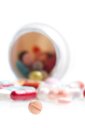 one small pill in laboratory in front of a colored pills on white tableの写真素材