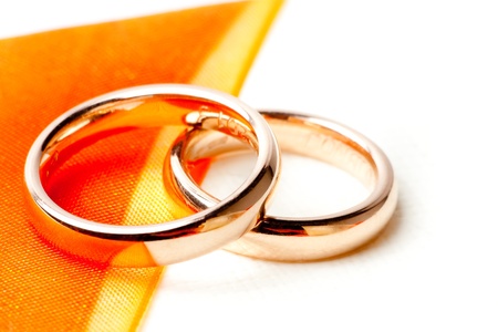 detail of gold wedding rings near orange ribbonの写真素材