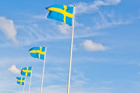 series of swedish flags with cloud and space for text against blue skyの写真素材