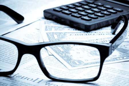 detail of dollars on business newspaper near calculator seen by unfocused glassesの写真素材