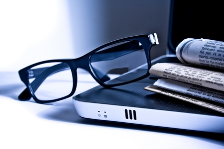 glasses on notebook near financial newspaperの写真素材