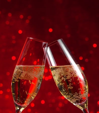  two champagne flutes make cheers on red light bokeh backgroundの写真素材