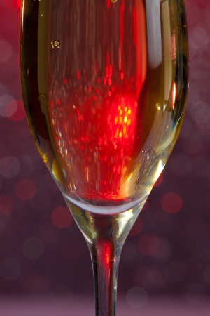 one half flute of champagne on red bokeh backgroundの写真素材