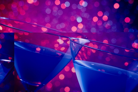 detail of a pair of glasses of blue cocktail on blue and violet tint light bokeh backgroundの写真素材