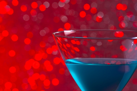 one glass blue cocktail on red tint light bokeh backgroundの写真素材