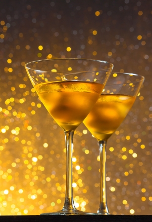 view from below of glasses of fresh cocktail with ice on golden tint light background on bar tableの写真素材