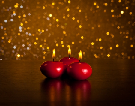 red christmas candles on wood table on golden bokeh background with space for textの写真素材