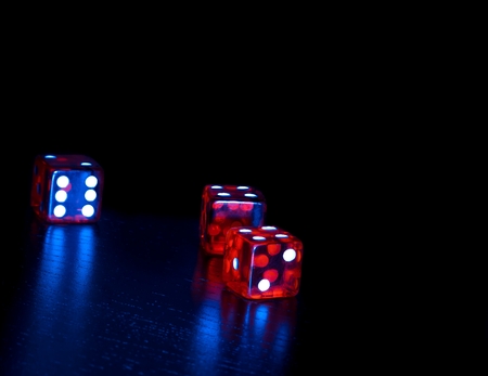 three red dice on old wood black table on light blue tint background with space for textの写真素材