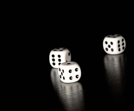three white dice on old wood black table on black background with space for textの写真素材