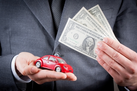 toy car and dollars in the hands of business man on white , concept for insurance, buying, renting, fuel or service and repair costsの写真素材