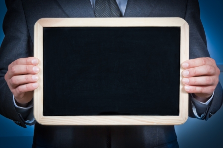 businessman holds a blank blackboard with the hands on a blue の写真素材