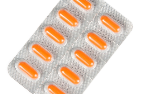 top of view of orange pills packed in blister isolated on white background