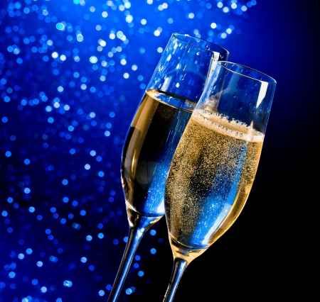 champagne flutes with golden bubbles on dark blue light bokeh background with space for textの写真素材