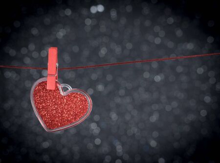 decorative red heart hanging against dark light bokeh background with space for text, concept of valentine dayの写真素材