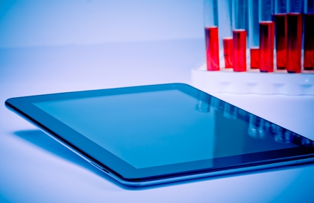 modern digital tablet pc near test tube in laboratory. Concept of medical or research theme
