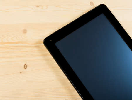 top of view of modern black tablet pc isolated on wood table with space for text