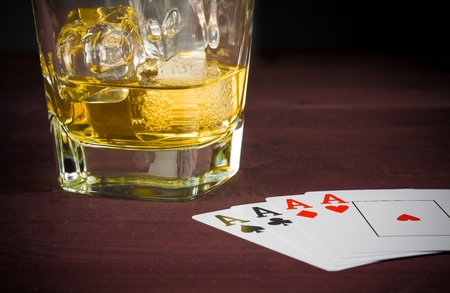 poker playing cards near wiskey glass on old wood table