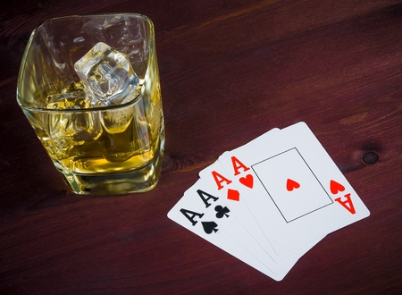 poker playing cards near wiskey glass on old wood table