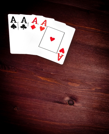 four aces of playing cards on old wood table with space for text, concept of poker game texas