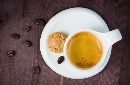 top of view of cup of cup of espresso coffee and biscuit near coffee beans on old woodの写真素材