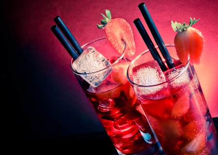 Strawberry cocktail with ice on wood table and space for text on blue and pink light disco club atmosphereの写真素材