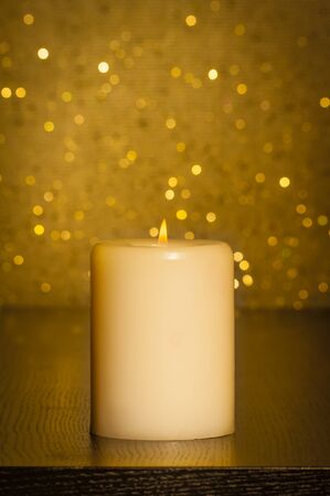 candle with flame on wood table and gold bokeh background and space for textの写真素材