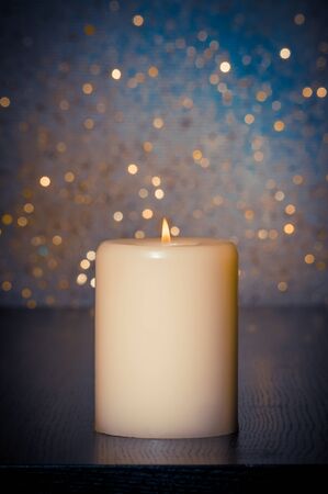 candle with flame on wood table and blue bokeh background and space for textの写真素材
