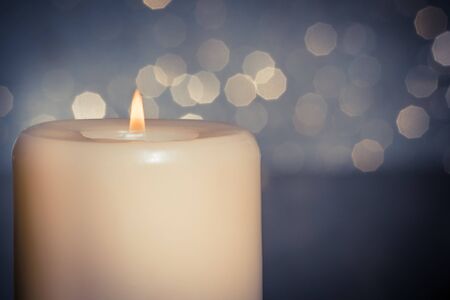 close-up of candle with flame on wood table and blue bokeh background and space for textの写真素材