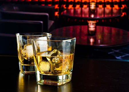 whiskey glasses with ice in a lounge bar on wood tableの写真素材