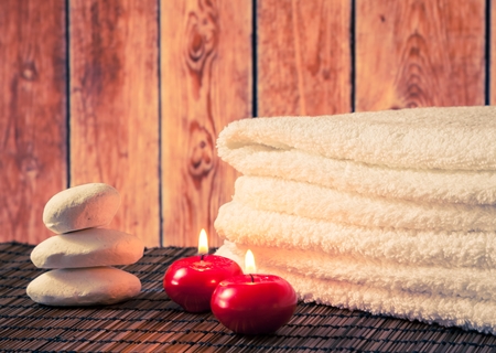 Spa massage border background with towel stacked stone and red candles on wood background warm atmosphereの写真素材