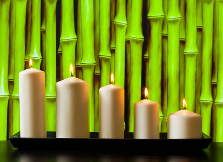 white candles on wood table and natural green bamboo backgroundの写真素材