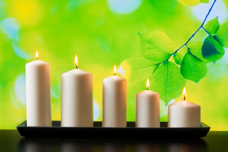 white candles on wood table and natural green backgroundの写真素材