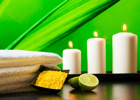 Spa massage border background with towel stacked sea salt candles and lime on natural green backgroundの写真素材